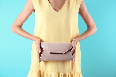 Young woman in stylish outfit with purse on color background, closeup