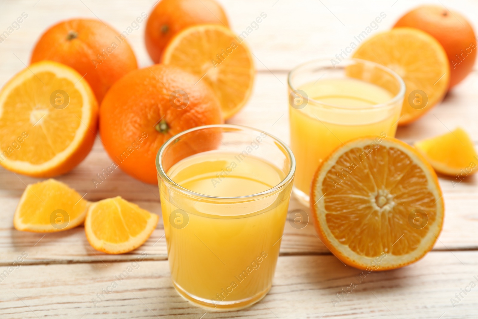 Photo of Delicious orange juice and fresh fruits on white wooden table, closeup