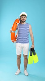 Sailor with ring buoy and swim fins on light blue background