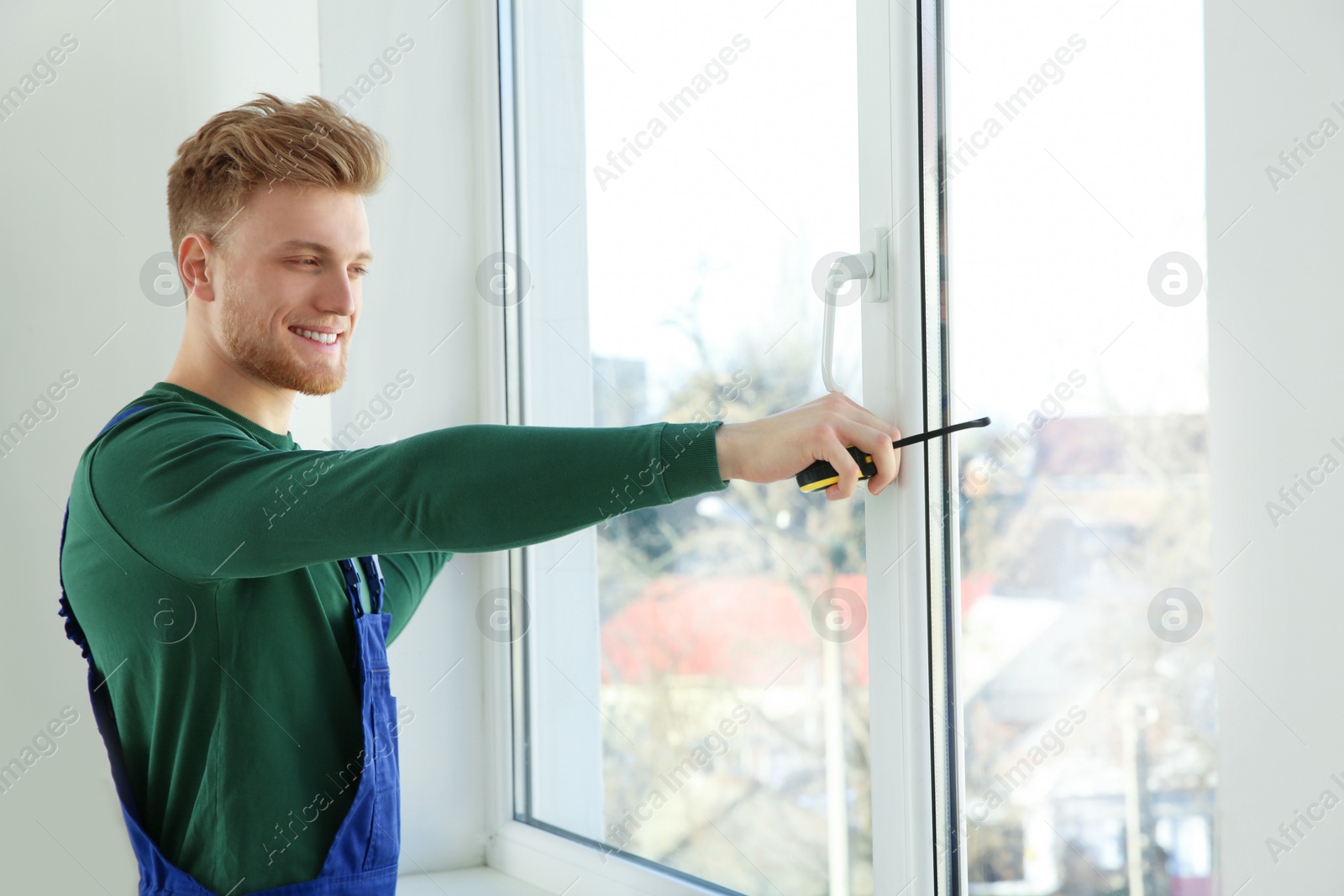 Photo of Service man measuring window for installation indoors