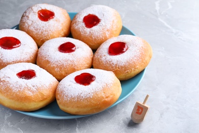 Photo of Hanukkah doughnuts with jelly and dreidel on grey table
