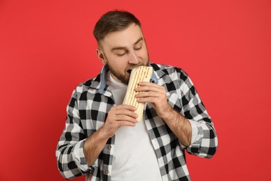 Photo of Young man eating delicious shawarma on red background