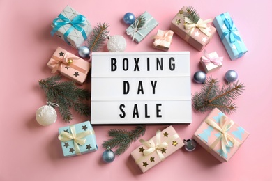 Photo of Lightbox with phrase BOXING DAY SALE and Christmas decorations on light pink background, flat lay