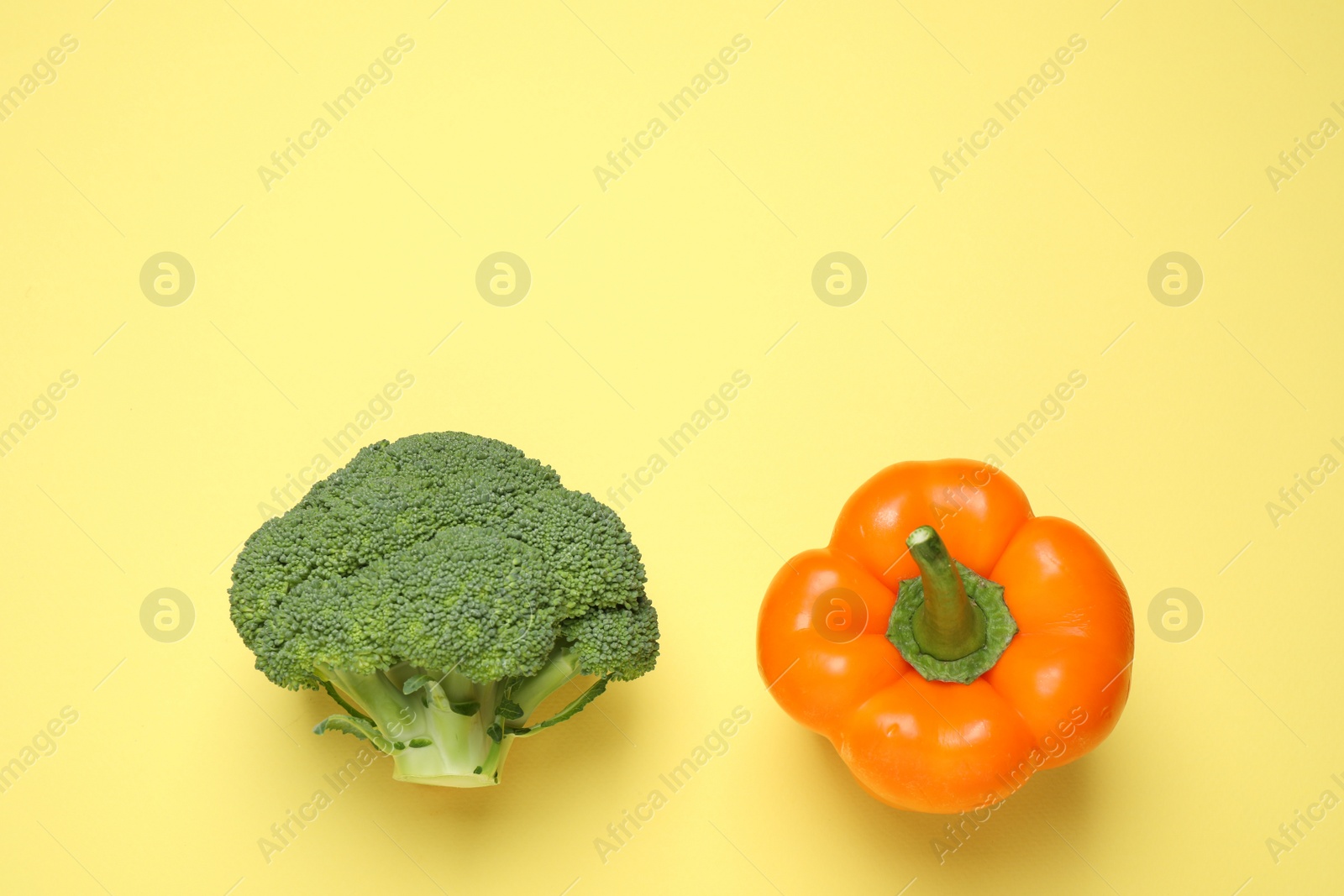 Photo of Fresh broccoli and bell pepper on yellow background, flat lay. Space for text