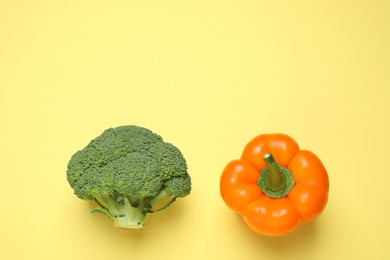 Photo of Fresh broccoli and bell pepper on yellow background, flat lay. Space for text