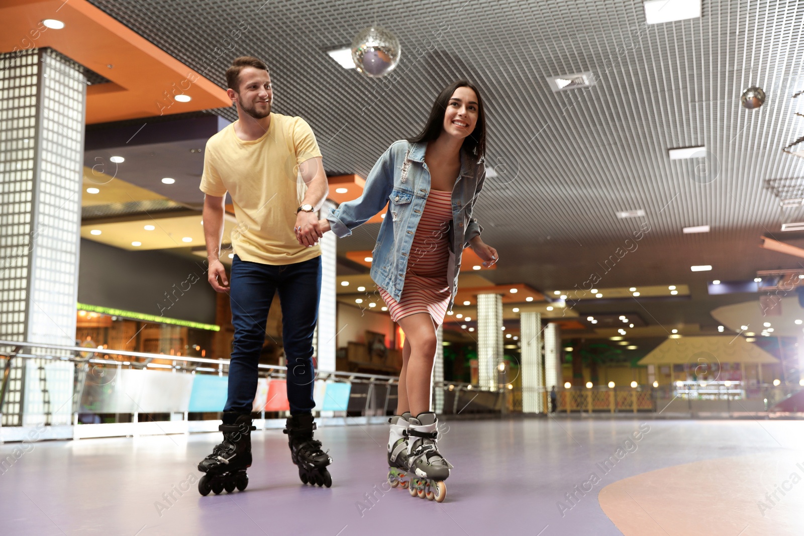 Photo of Young couple spending time at roller skating rink