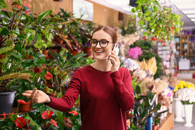 Photo of Female business owner talking on mobile phone in flower shop
