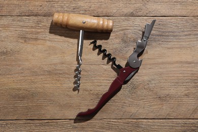 Different corkscrews on wooden table, flat lay