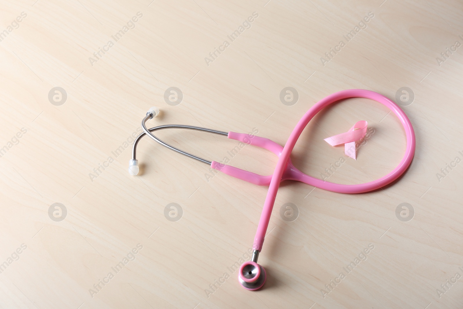 Photo of Pink ribbon with stethoscope on wooden background. Breast cancer concept