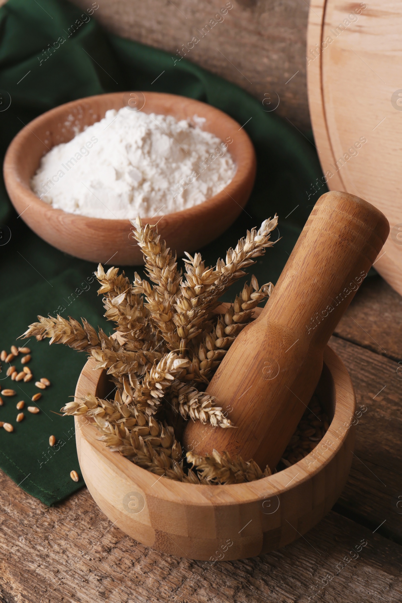 Photo of Mortar with spikes and bowl of wheat flour on wooden table