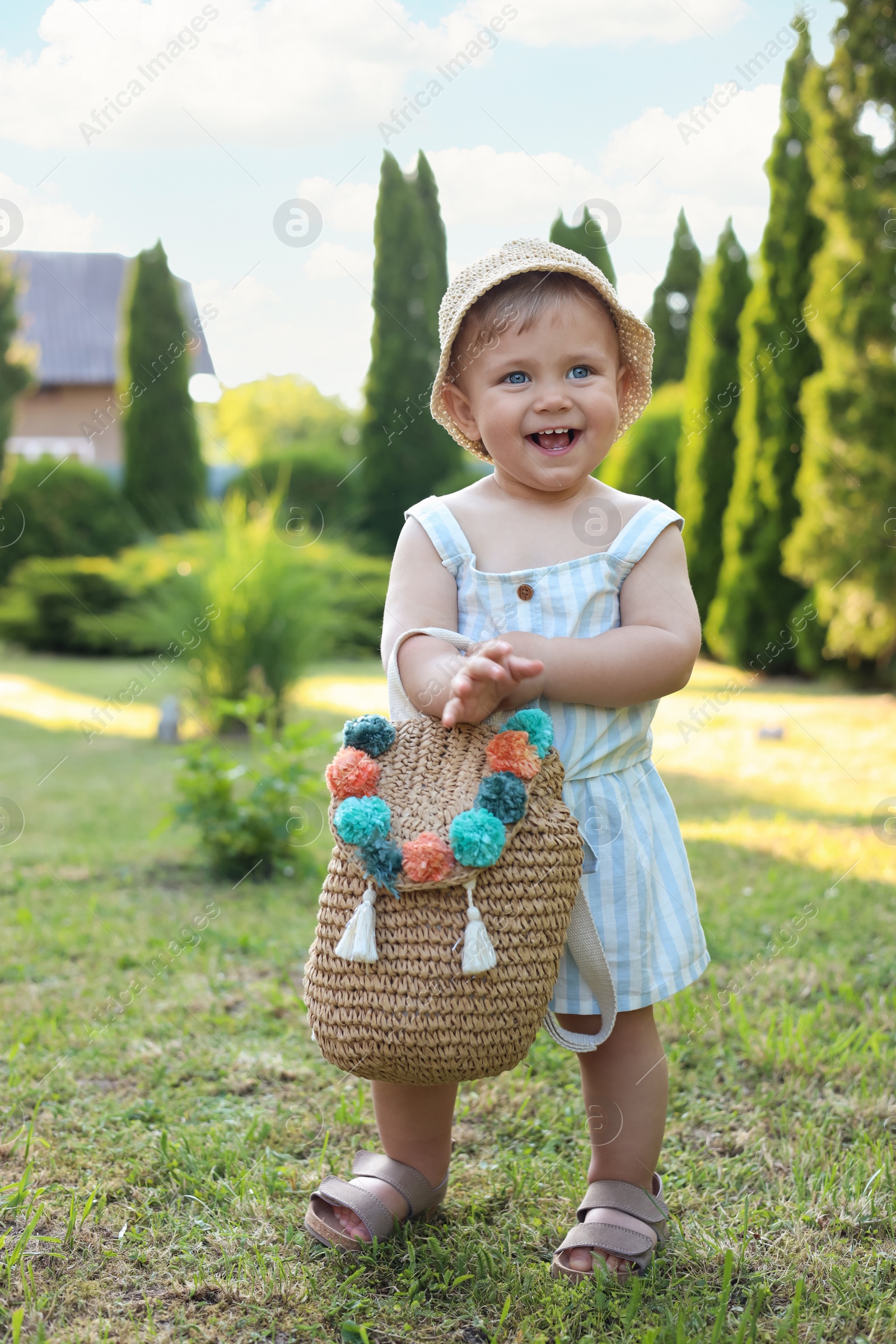 Photo of Cute little girl in stylish clothes with knitted backpack outdoors on sunny day