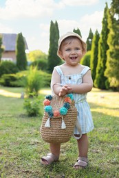 Photo of Cute little girl in stylish clothes with knitted backpack outdoors on sunny day