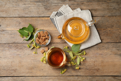 Photo of Flat lay composition with tasty tea and linden blossom on wooden table