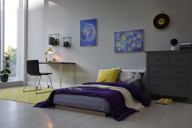 Modern teenager's room interior with comfortable bed, workplace and stylish design elements