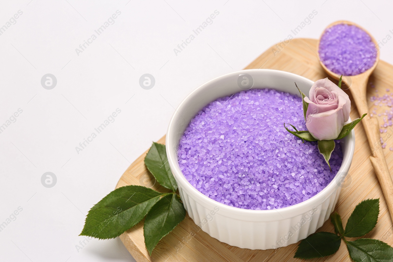 Photo of Bowl and spoon with sea salt, beautiful rose with green leaves on white background. Space for text