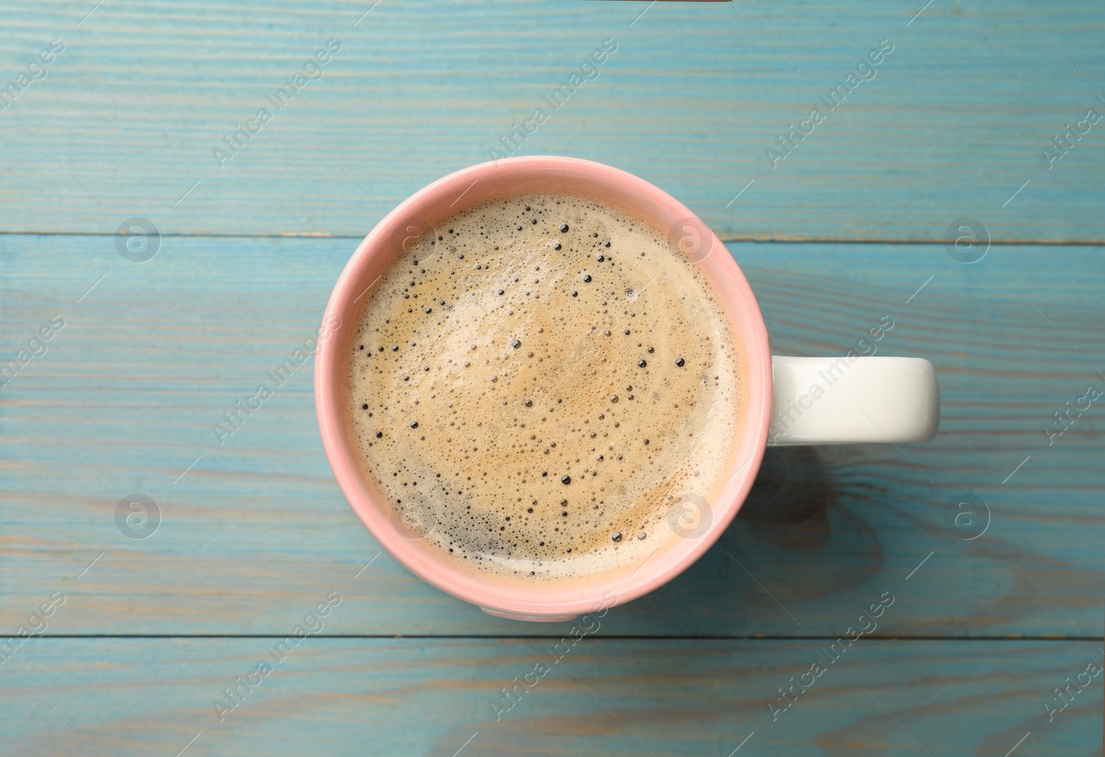 Photo of Cup of aromatic coffee on light blue wooden table, top view