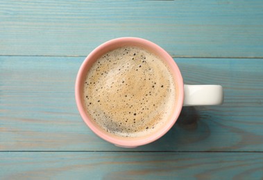 Cup of aromatic coffee on light blue wooden table, top view