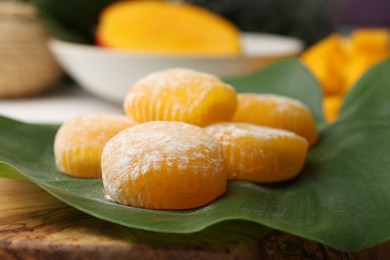 Photo of Delicious mochi with green leaf on wooden board, closeup. Traditional Japanese dessert