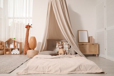 Cozy kids room with play tent, toys and comfortable floor bed. Montessori interior