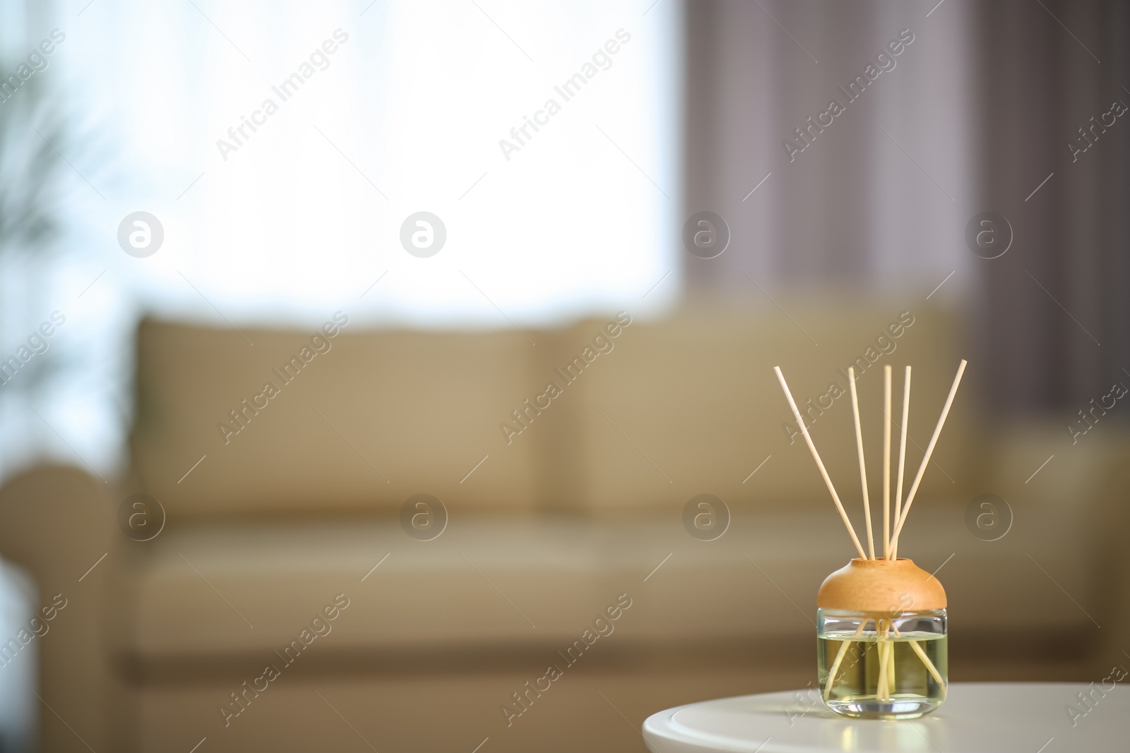 Photo of Aromatic reed air freshener on table indoors. Space for text