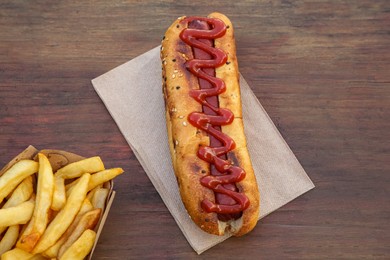 Photo of Fresh tasty hot dog and french fries on wooden table, flat lay