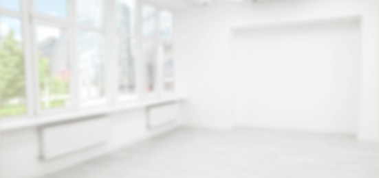 Empty room with white wall and large window, blurred view. Banner design