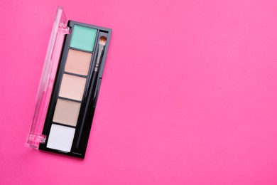 Photo of Colorful contouring palette and brush on pink background, top view with space for text. Professional cosmetic product