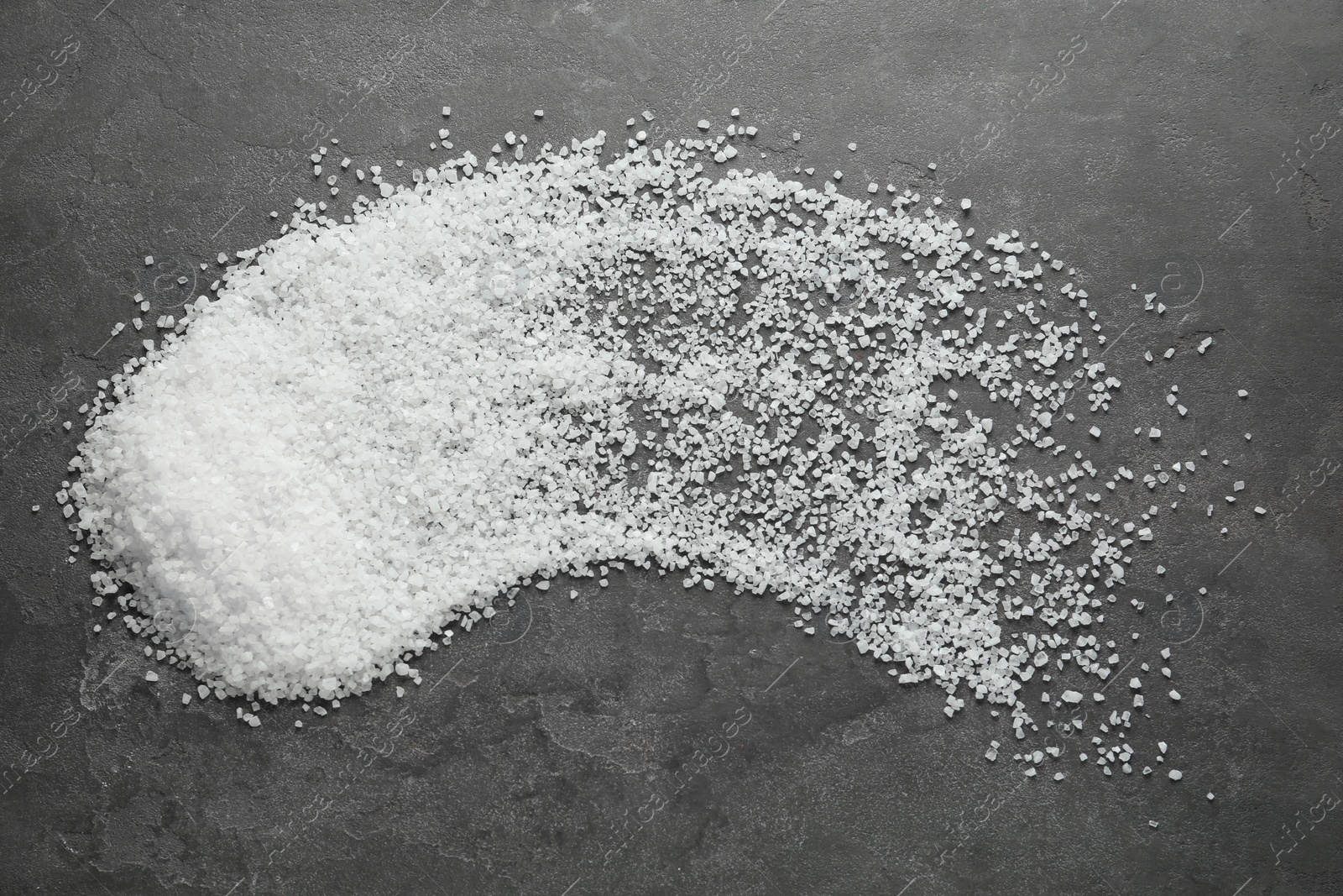 Photo of Natural sea salt on grey table, flat lay