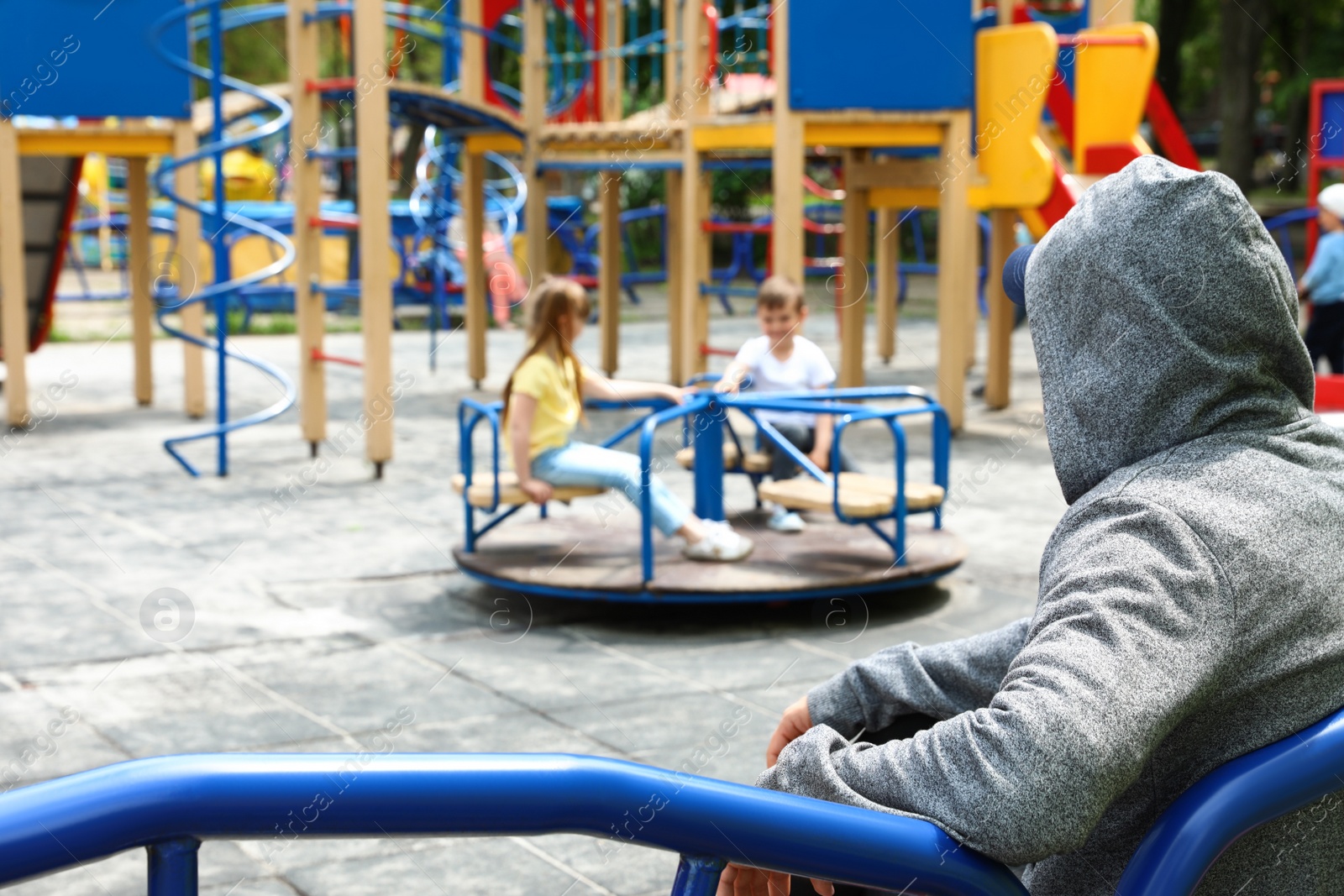 Photo of Suspicious adult man spying on kids at playground, space for text. Child in danger