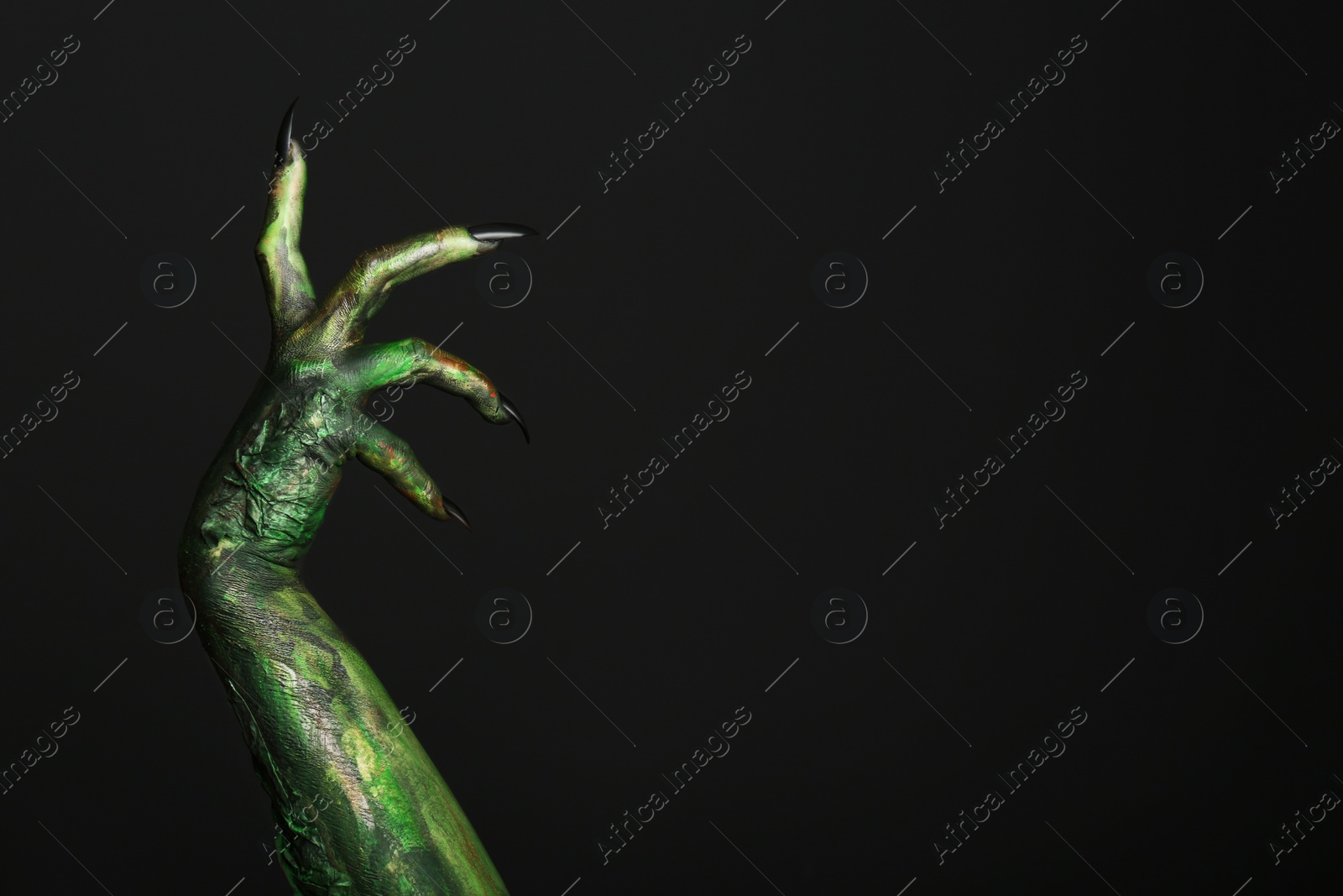 Photo of Scary monster on black background, closeup of hand with space for text. Halloween character