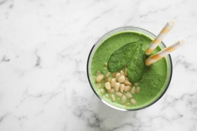 Photo of Glass of healthy green smoothie with fresh spinach on marble table, top view. Space for text