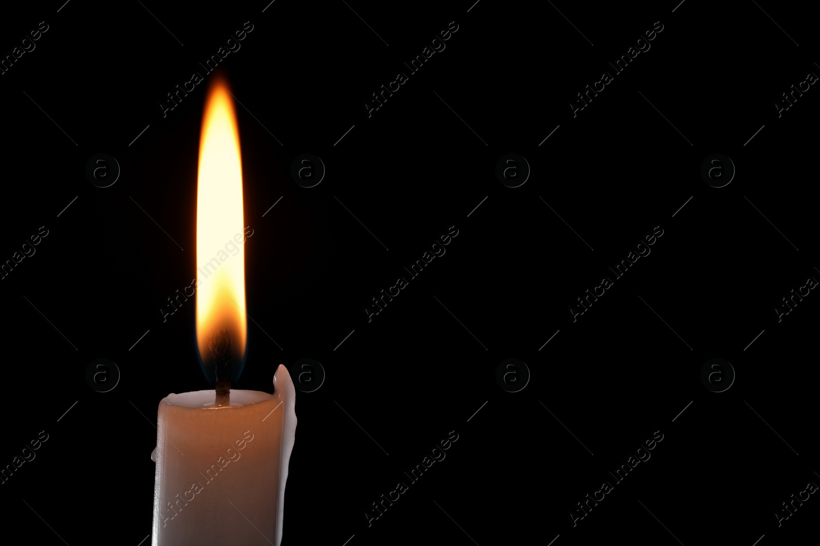 Photo of Burning candle on black background, closeup. Space for text