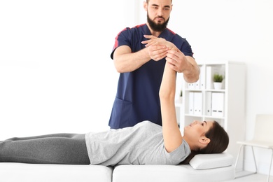 Photo of Physiotherapist working with young female patient in clinic