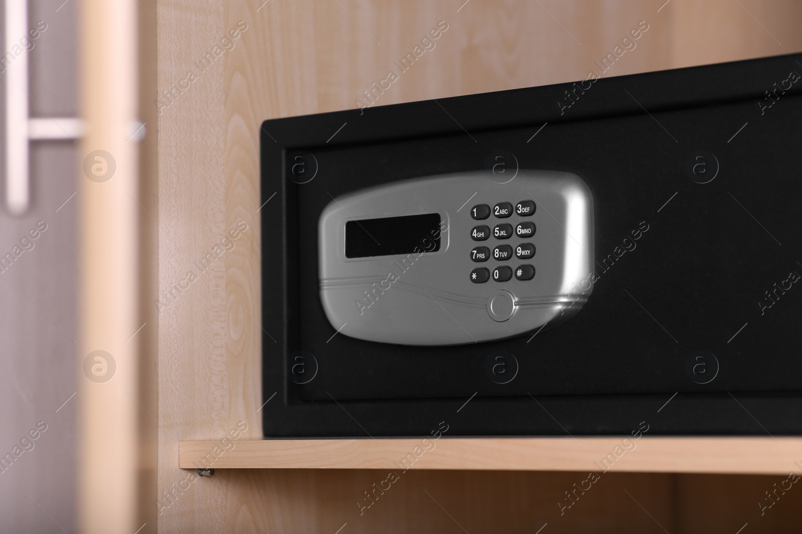 Photo of Black steel safe with electronic lock in wooden closet at hotel