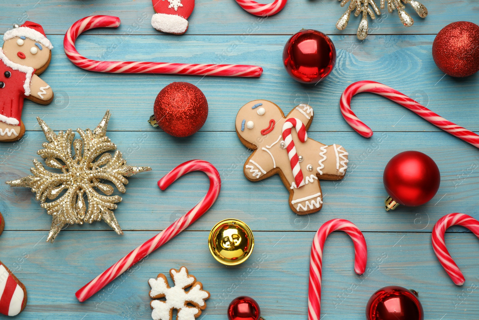 Photo of Flat lay composition with tasty candy canes and Christmas decor on light blue wooden table