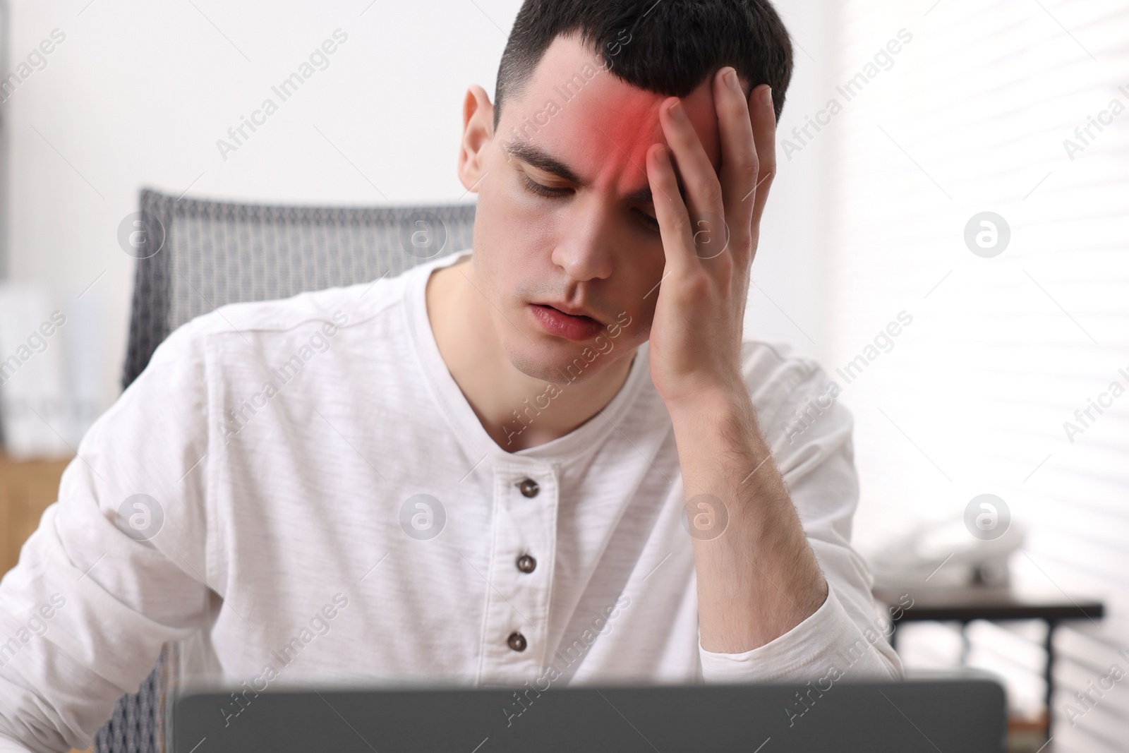 Image of Young man suffering from headache in room