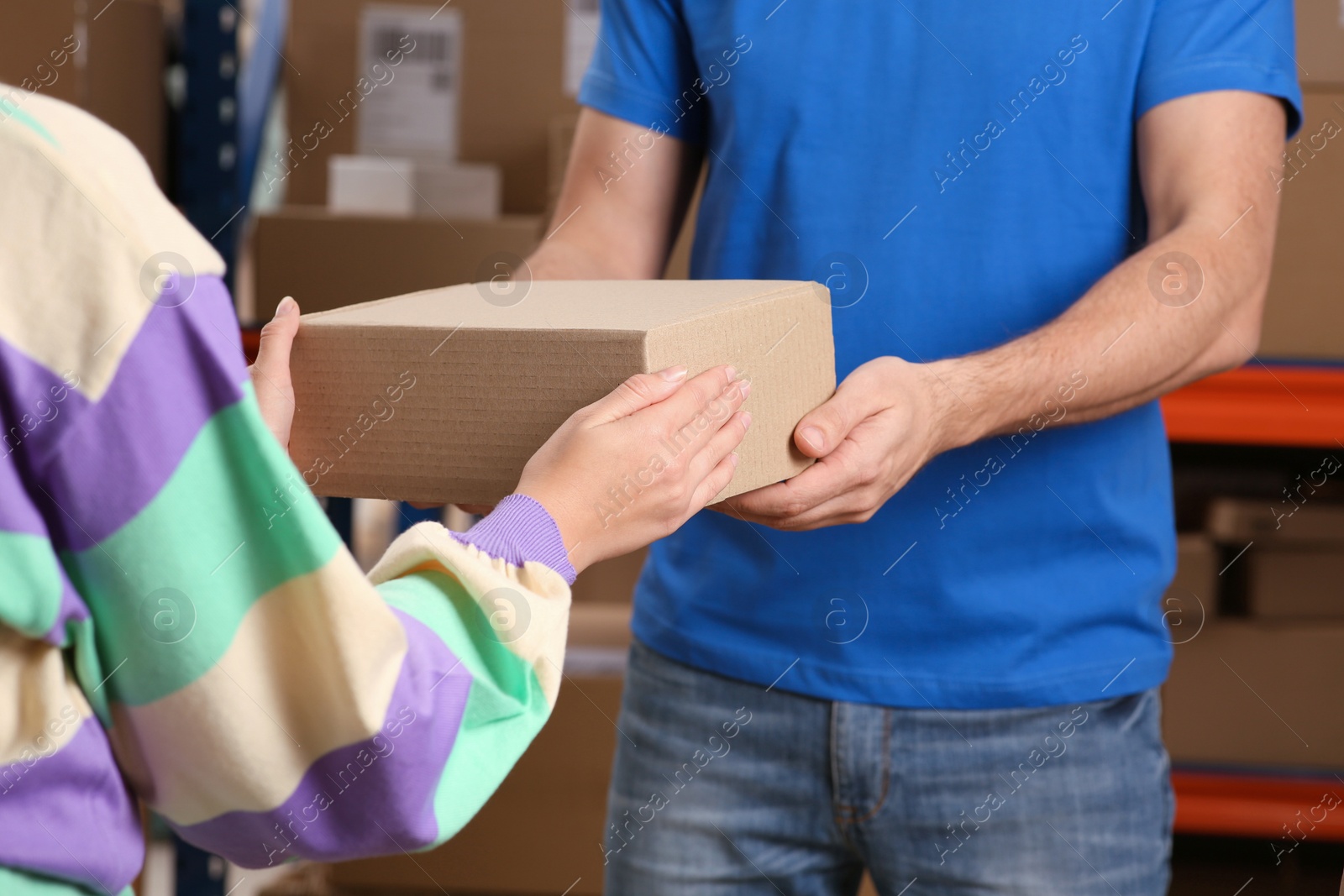 Photo of Worker giving parcel to woman at post office, closeup