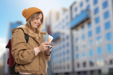 Image of Happy traveler with camera and map in foreign city. Vacation trip