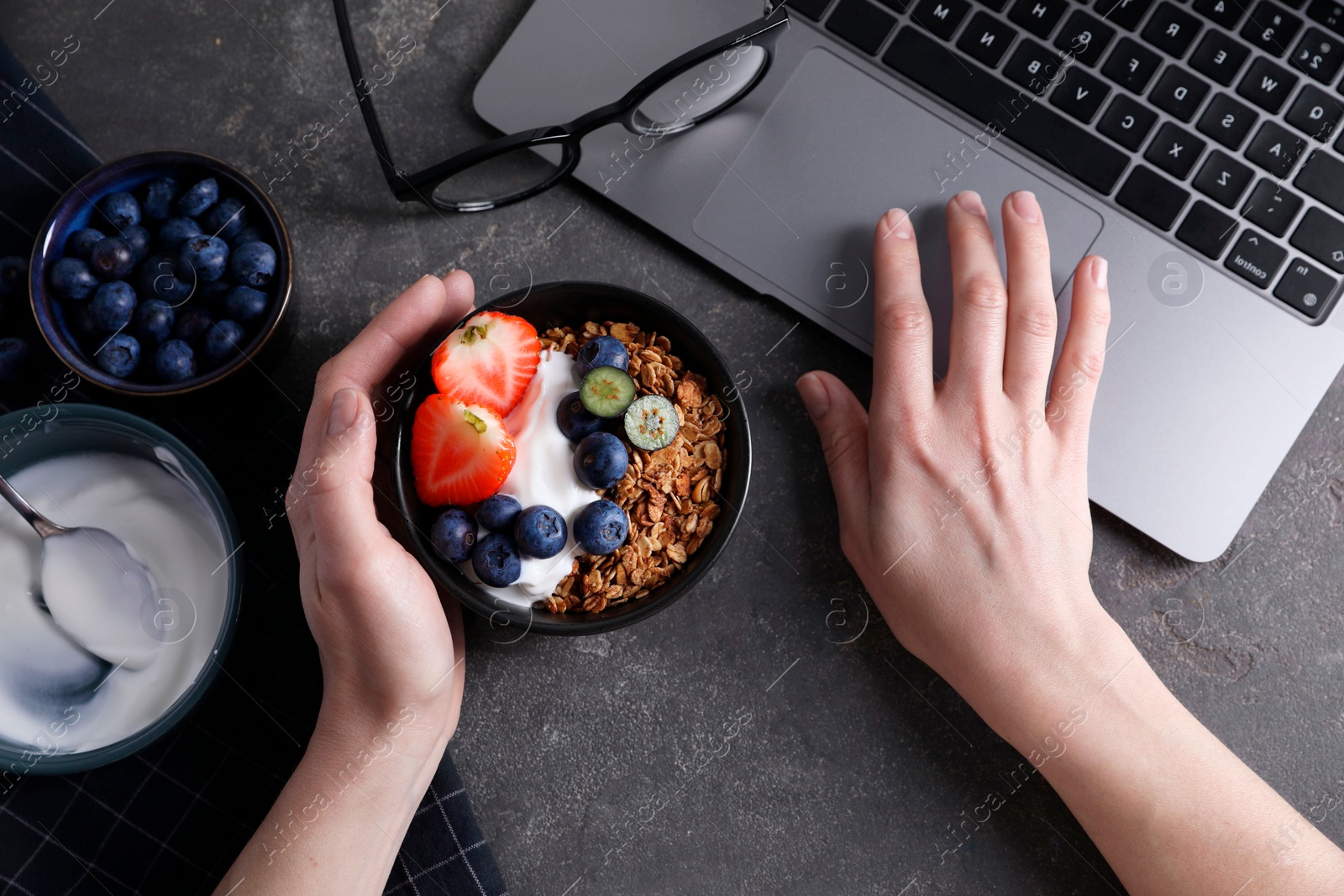 Photo of Woman with tasty granola at workplace, top view