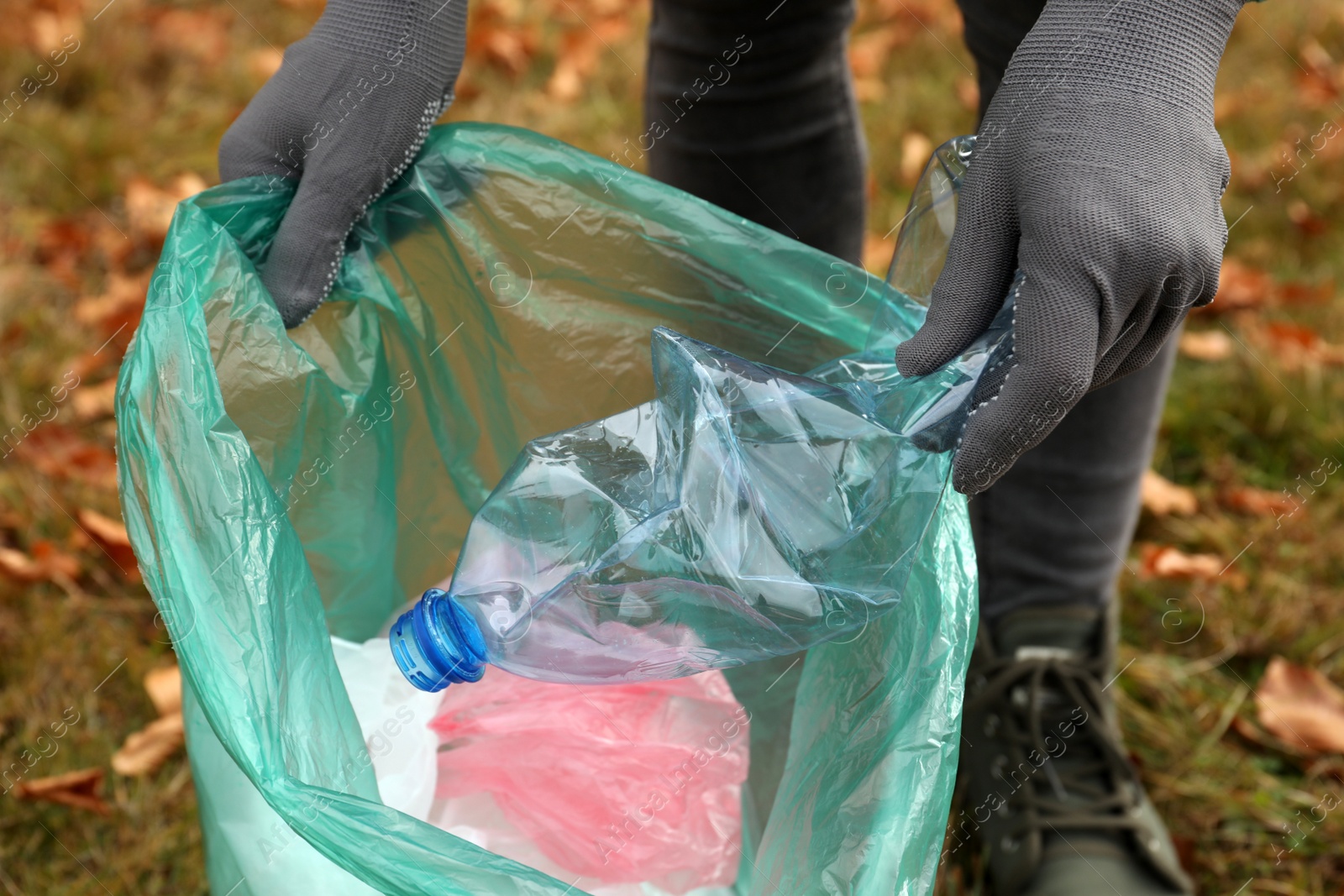 Photo of Woman with trash bag collecting garbage in nature, closeup