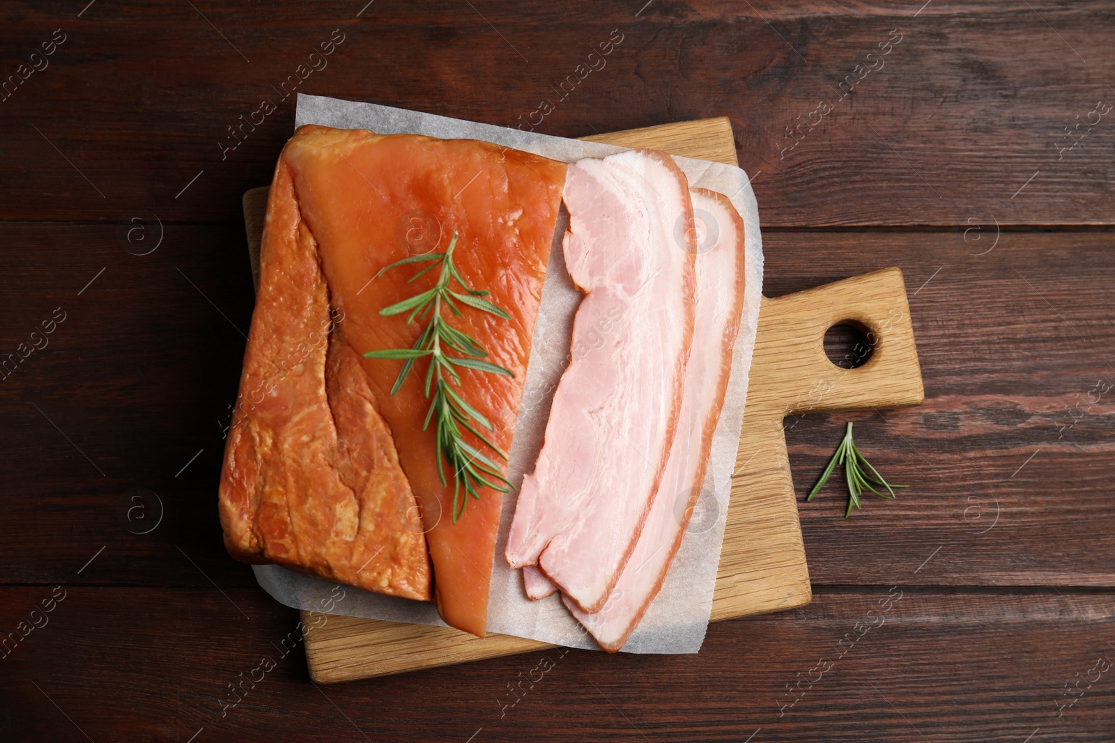 Photo of Delicious smoked bacon with rosemary on wooden table, flat lay