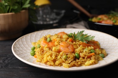 Photo of Tasty rice with shrimps and vegetables on dark wooden table, closeup
