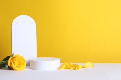 Beautiful presentation for product. Geometric figures and rose on white table against yellow background, space for text