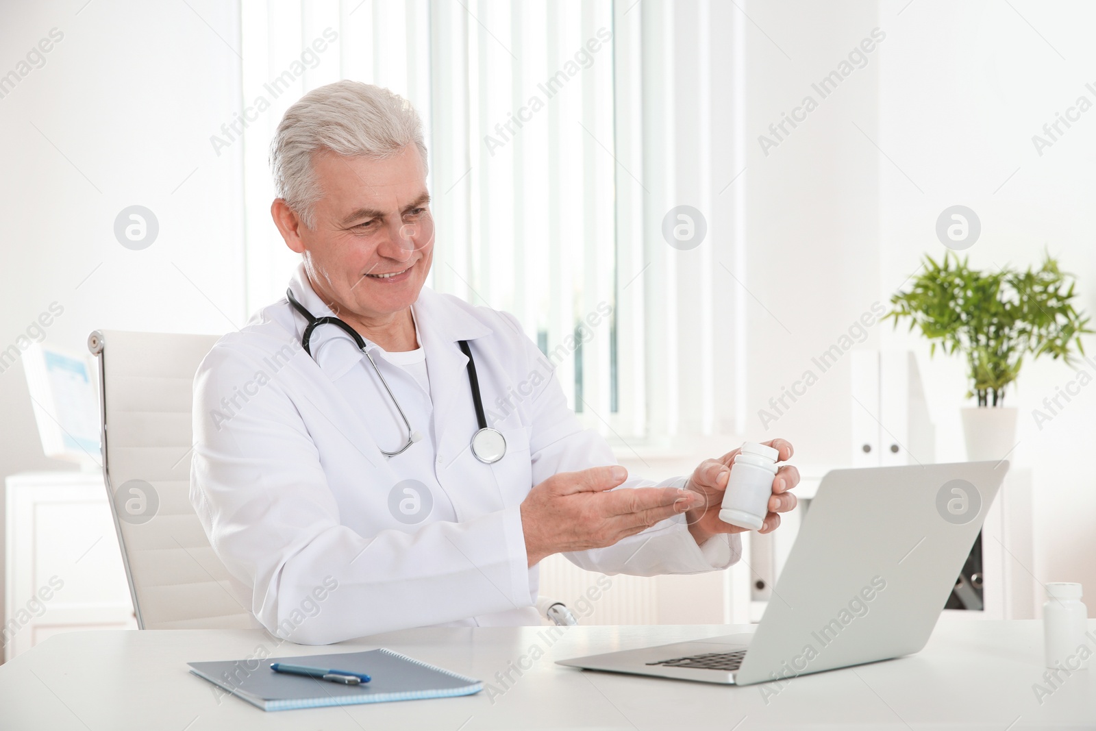 Photo of Doctor consulting patient using video chat on laptop in clinic