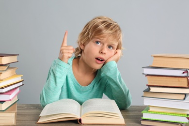 Photo of Little boy doing homework at table on grey background