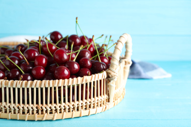 Photo of Sweet juicy cherries on light blue wooden table, closeup