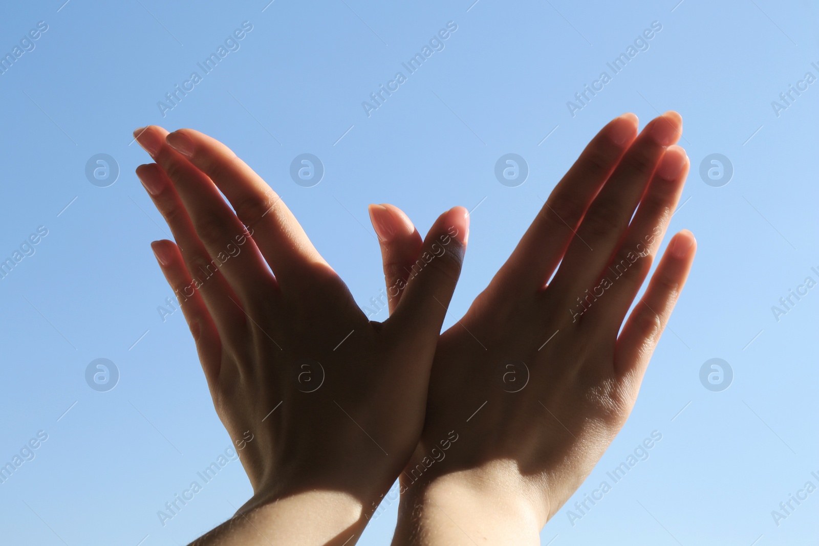 Photo of Woman making hand gesture like bird on light blue background, closeup