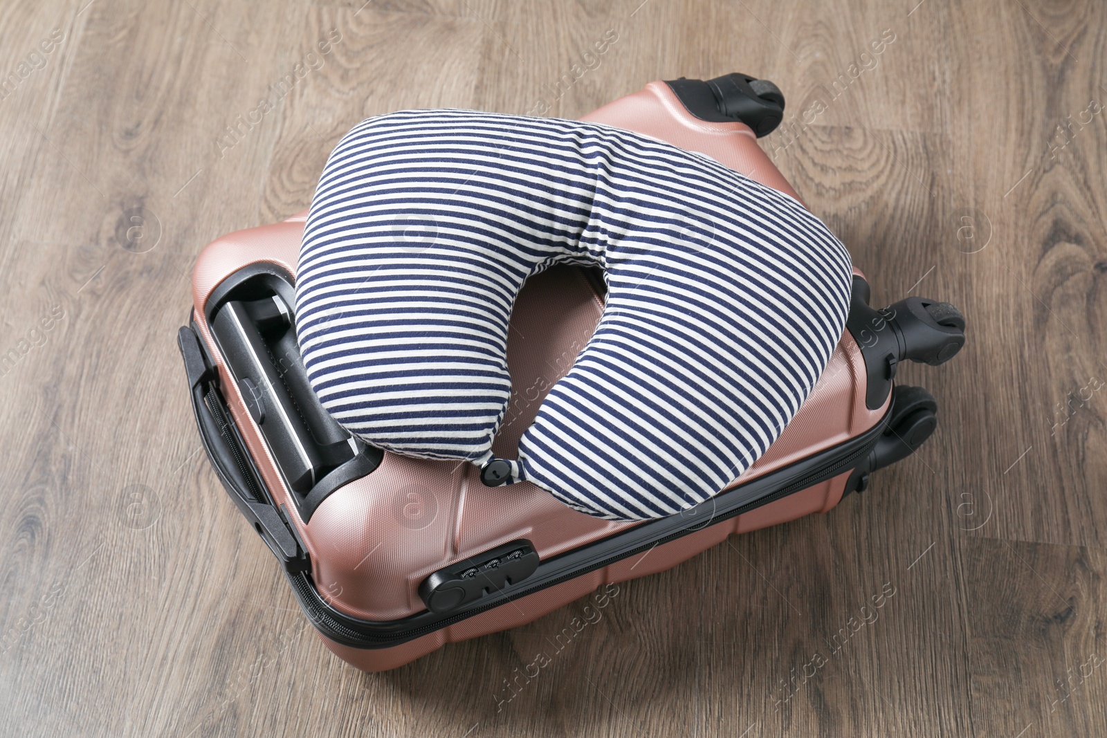 Photo of Striped travel pillow and suitcase on floor