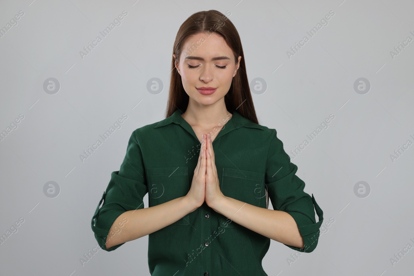 Photo of Woman with clasped hands praying on light grey background