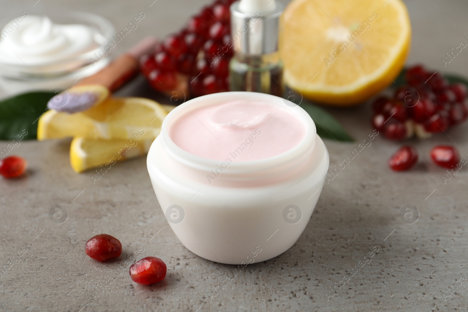 Photo of Natural facial mask and pomegranate seeds on light grey table, closeup